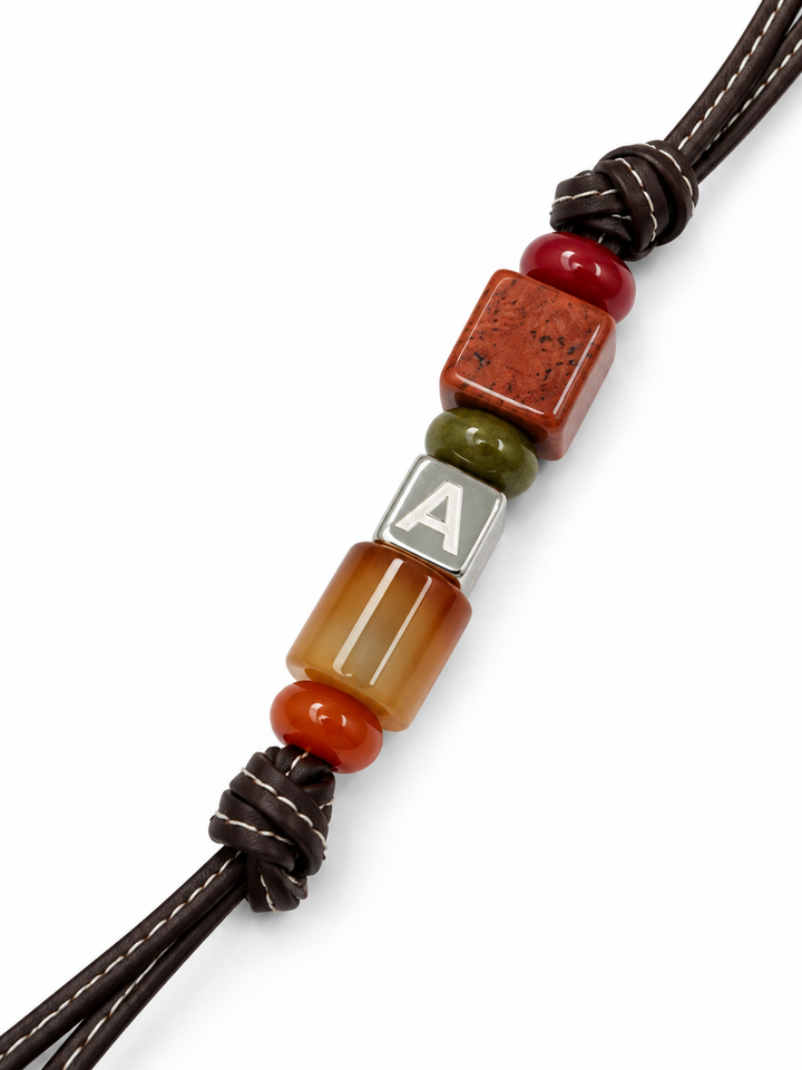Ember leather bag charm close-up with red stones and initial letter cube